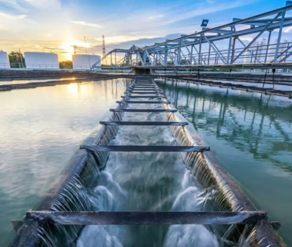 Industrielle Wasseraufbereitungsanlage mit Sedimentationsbecken und Reinigungskanälen bei Sonnenuntergang.