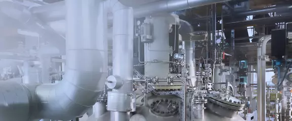 Industrielle Prozessanlage mit Rohrleitungen, Behältern und Armaturen in einer modernen Produktionsumgebung.