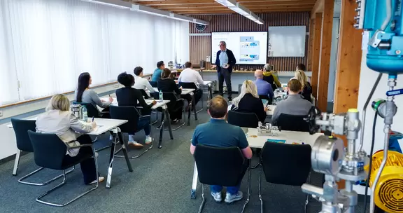 Professionelles Seminar mit Referent und Teilnehmenden in einem modernen Schulungsraum.