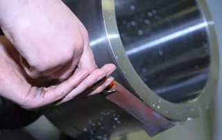 Worker polishing a metal component of a mechanical seal, illustrating EagleBurgmann Germany’s safety initiative that reduced manual polishing and workplace injuries through automation.