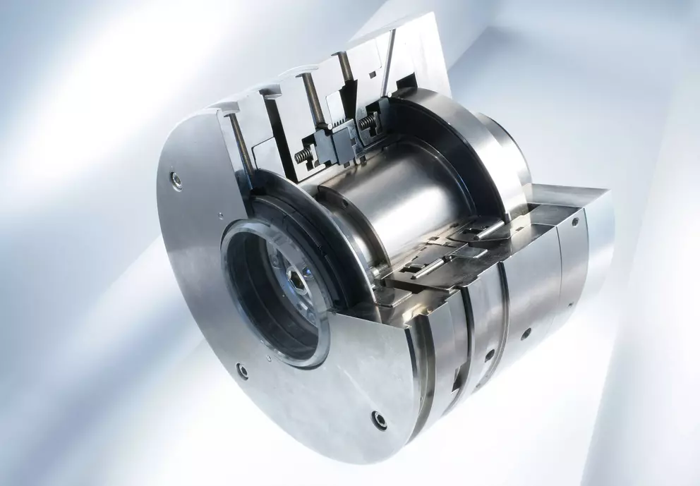 A close-up cutaway view of a large, complex mechanical seal for industrial equipment, made of polished metal, revealing the inner workings and chambers.
