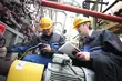 Engineers in safety helmets inspecting industrial equipment and mechanical seals during maintenance work at a processing plant.