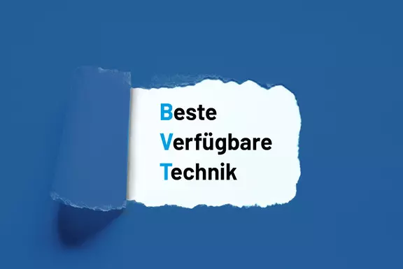 Aufgerissenes Papier, das den Text „Best Available Technique (BAT)“ auf blauem Hintergrund freilegt.