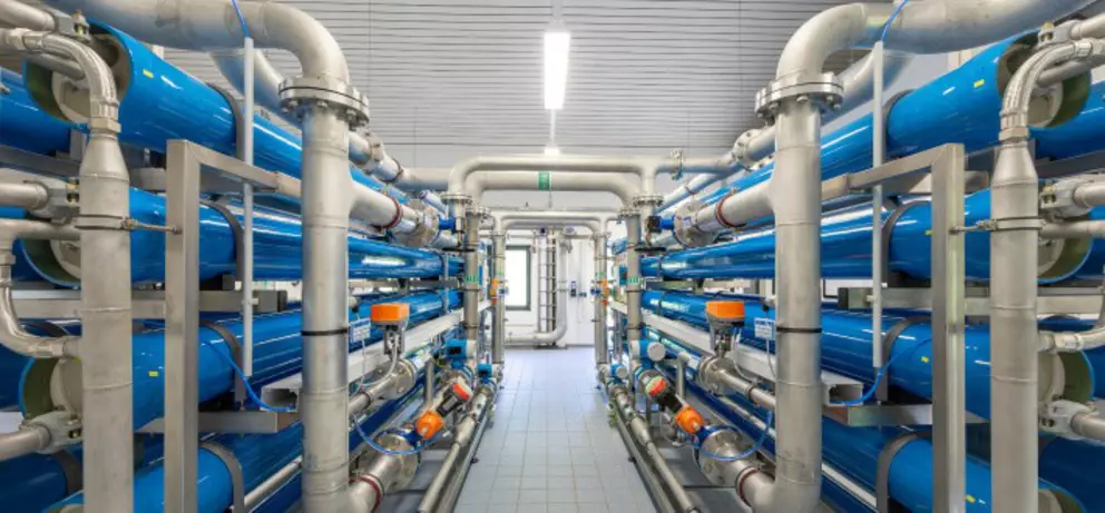Industrielles Umkehrosmose-Wasseraufbereitungssystem mit blauen Filterrohren und Edelstahlanschlüssen.