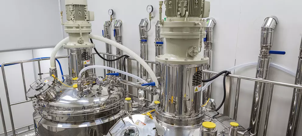 Stainless steel mixing tanks with motors and gauges in a clean industrial facility.