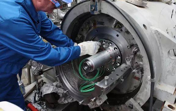 Technician performing maintenance on a large industrial rotor assembly and installing sealing components.