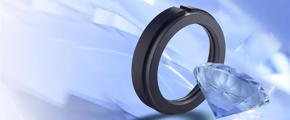 A black mechanical sealing ring positioned upright next to a large, blue, faceted diamond on a light blue abstract background with prism-like reflections.