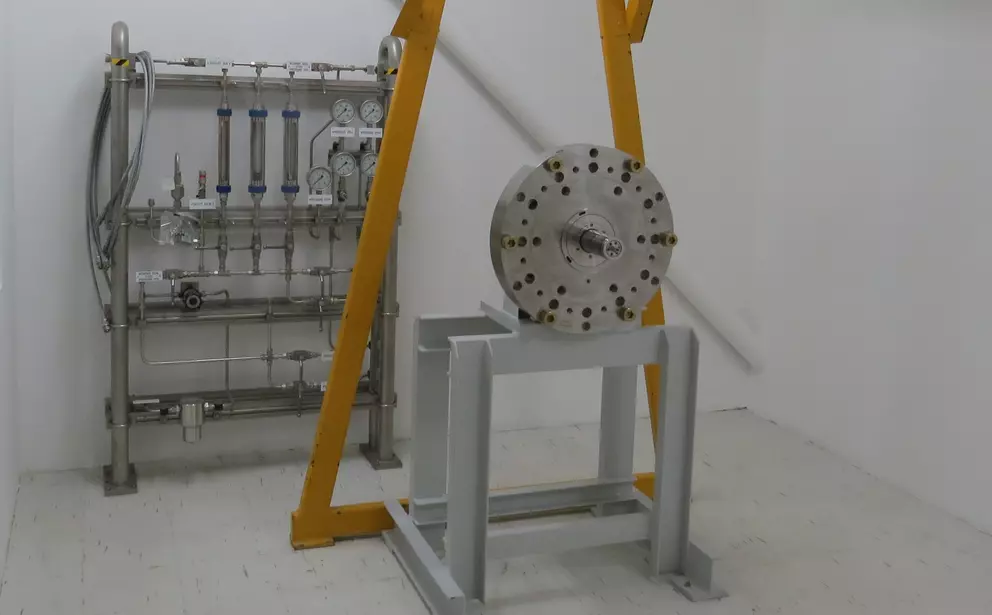 Industrial test setup with a large sealing housing mounted on a support frame and a connected measurement and control panel in the background.