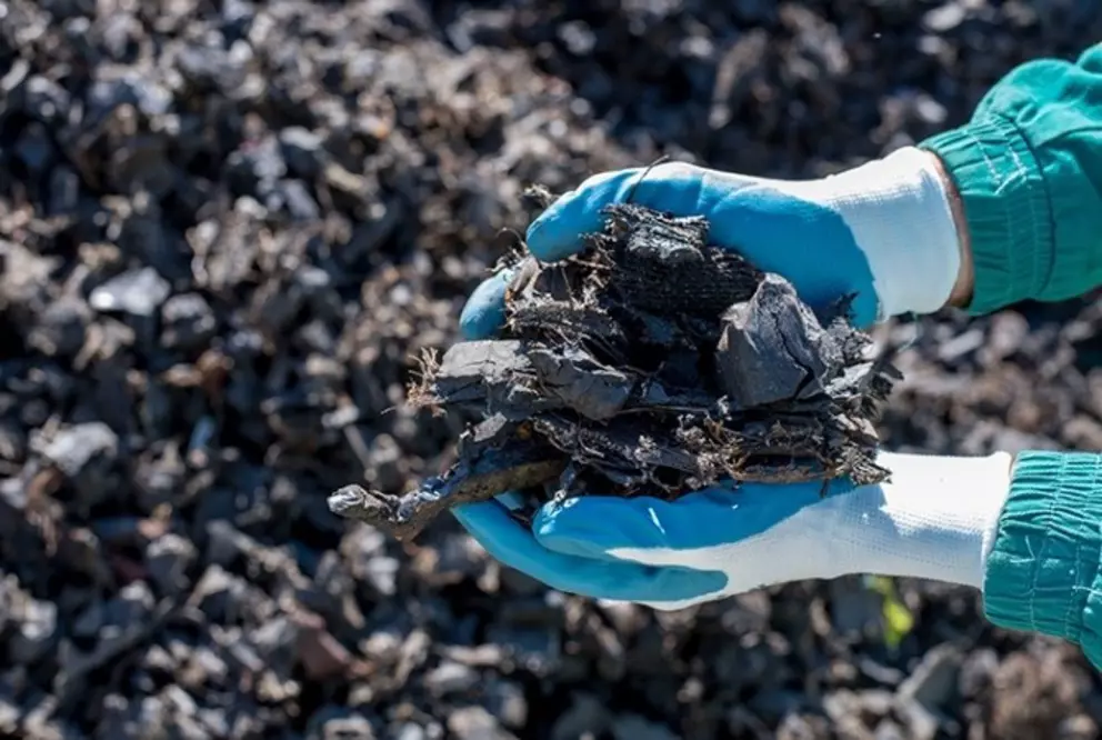 Hände, die zerkleinertes Kunststoffabfallmaterial zum Recycling halten.