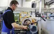 Technician operating industrial machinery in an EagleBurgmann workshop, inspecting and machining a mechanical sealing component in a modern production environment.