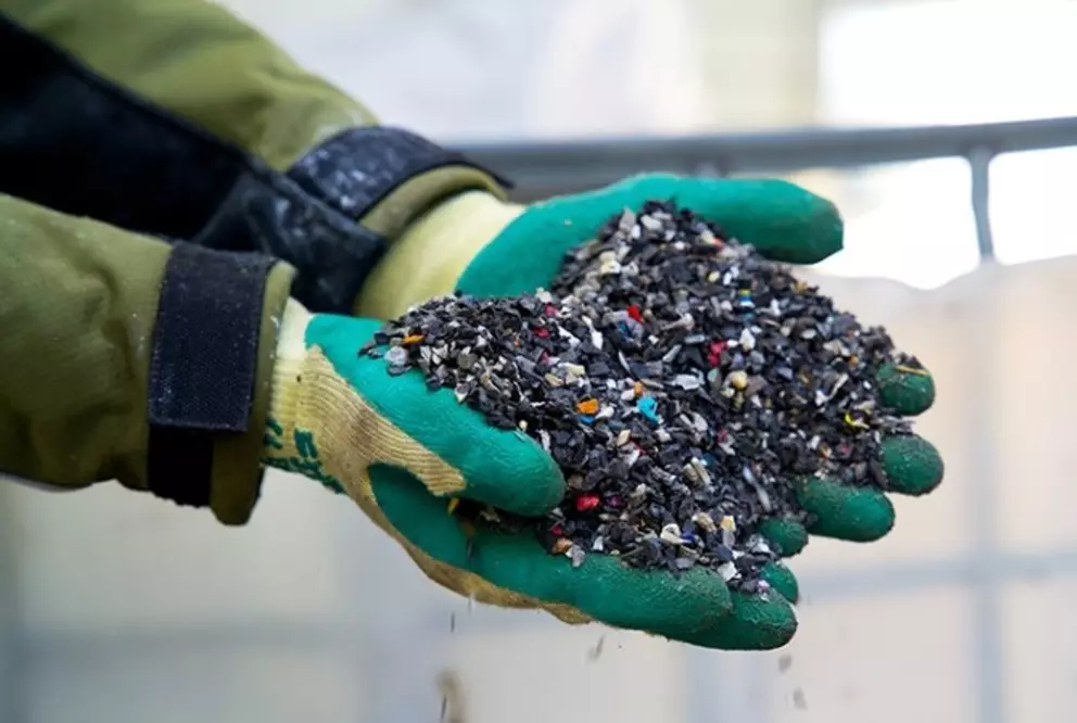 Hände, die recycelte Kunststoffgranulate für die Wiederverwendung in der Produktion halten.