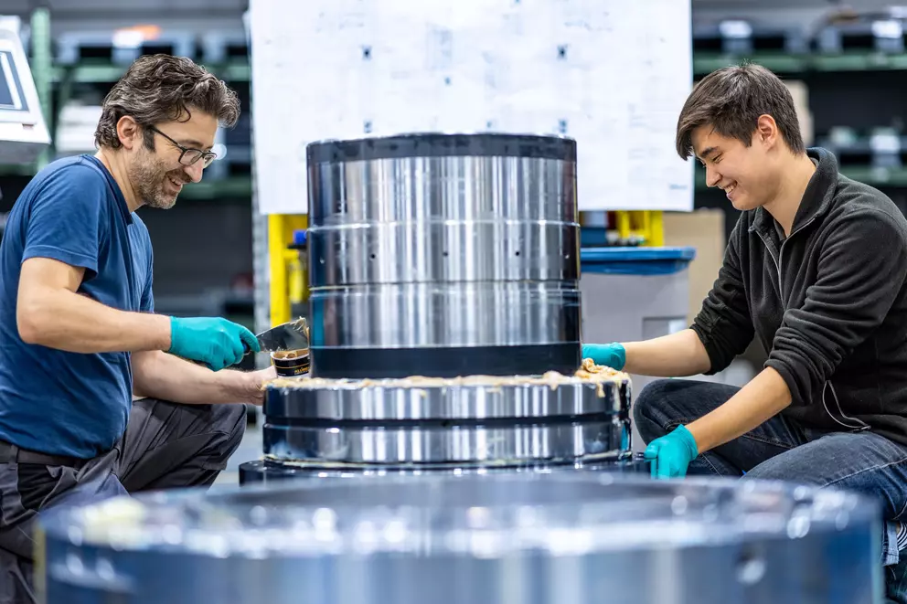EagleBurgmann-Techniker bei der Montage und dem Auftragen von Dichtungsmaterial an einer großen industriellen Gleitringdichtung – zeigt Präzisionsengineering, Teamarbeit und Fertigungskompetenz.