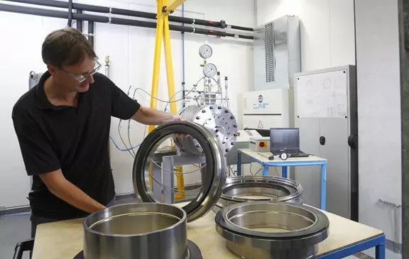Technician inspecting large precision rings in an industrial testing laboratory.