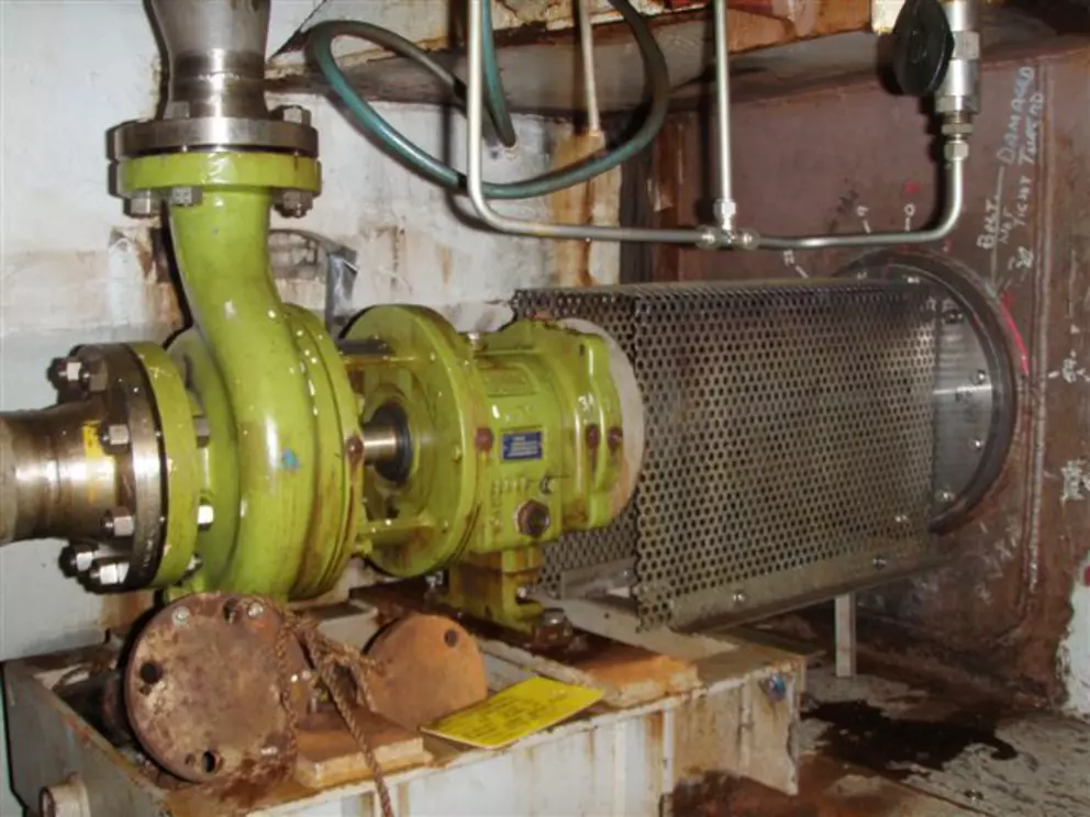 Industrial pump system with protective coupling guard in a plant environment.