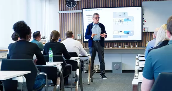 Professional seminar with a presenter and participants in a modern training room.