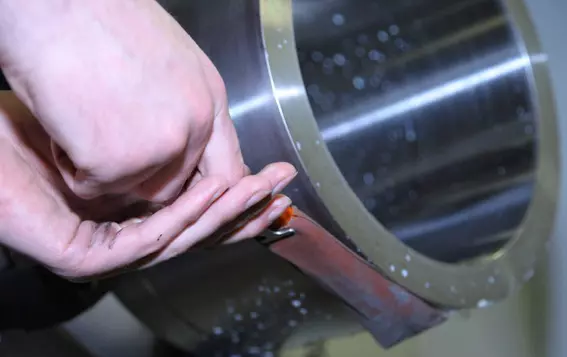 Worker polishing a metal component of a mechanical seal, illustrating EagleBurgmann Germany’s safety initiative that reduced manual polishing and workplace injuries through automation.