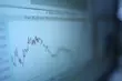 Blurred close-up of a computer screen displaying a fluctuating line graph or measurement curve.