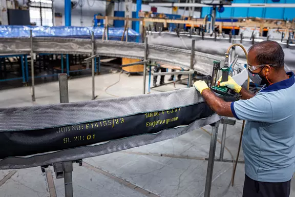 Fabrikmitarbeiter bei der Prüfung und Montage eines großen Gewebekompensators für industrielle Luftkanäle und Hochtemperatur-Dichtungsanwendungen.